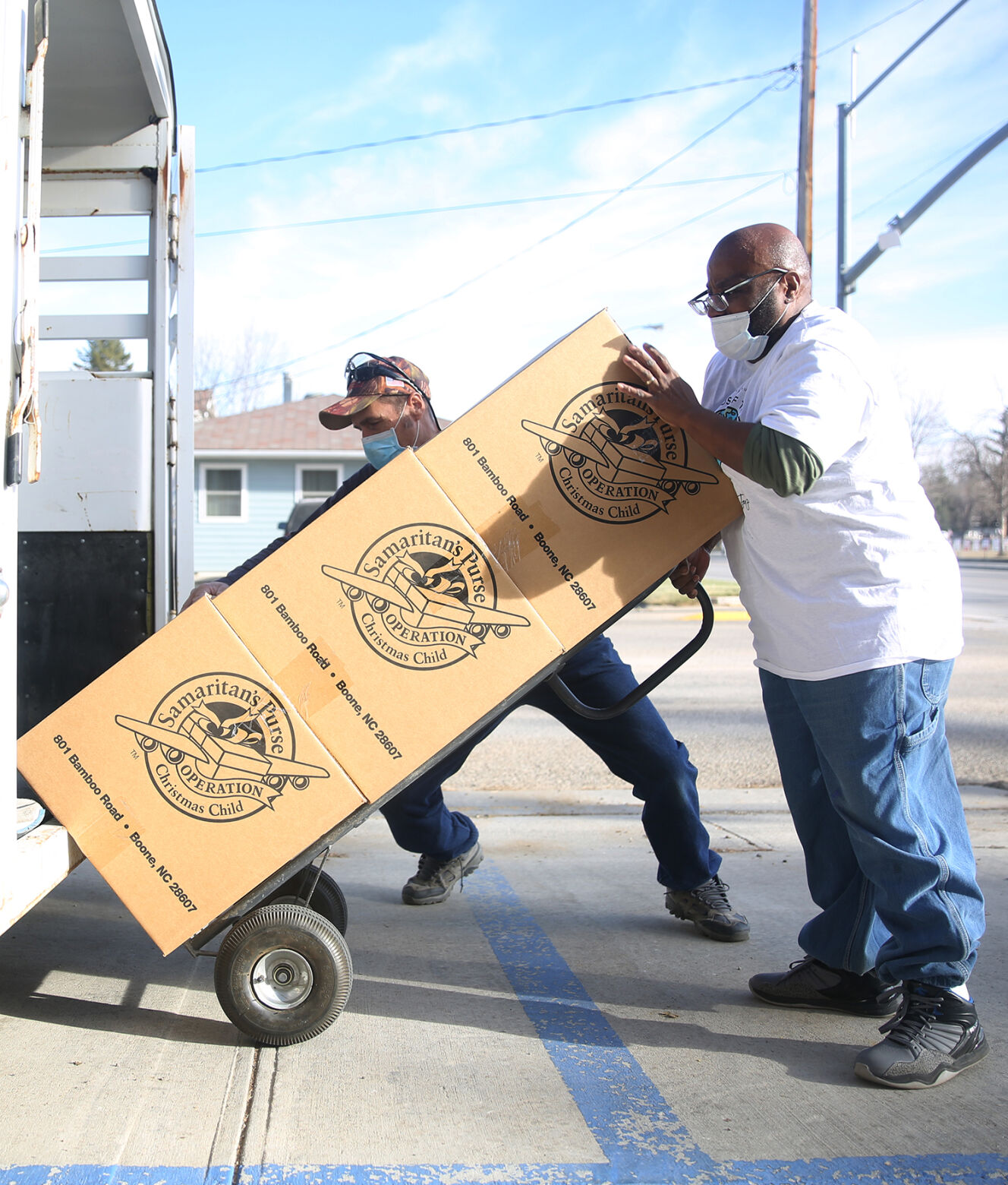 Gabryl Lewis pushes the stack of boxes up into the trailer with the help of Dennis Thorson